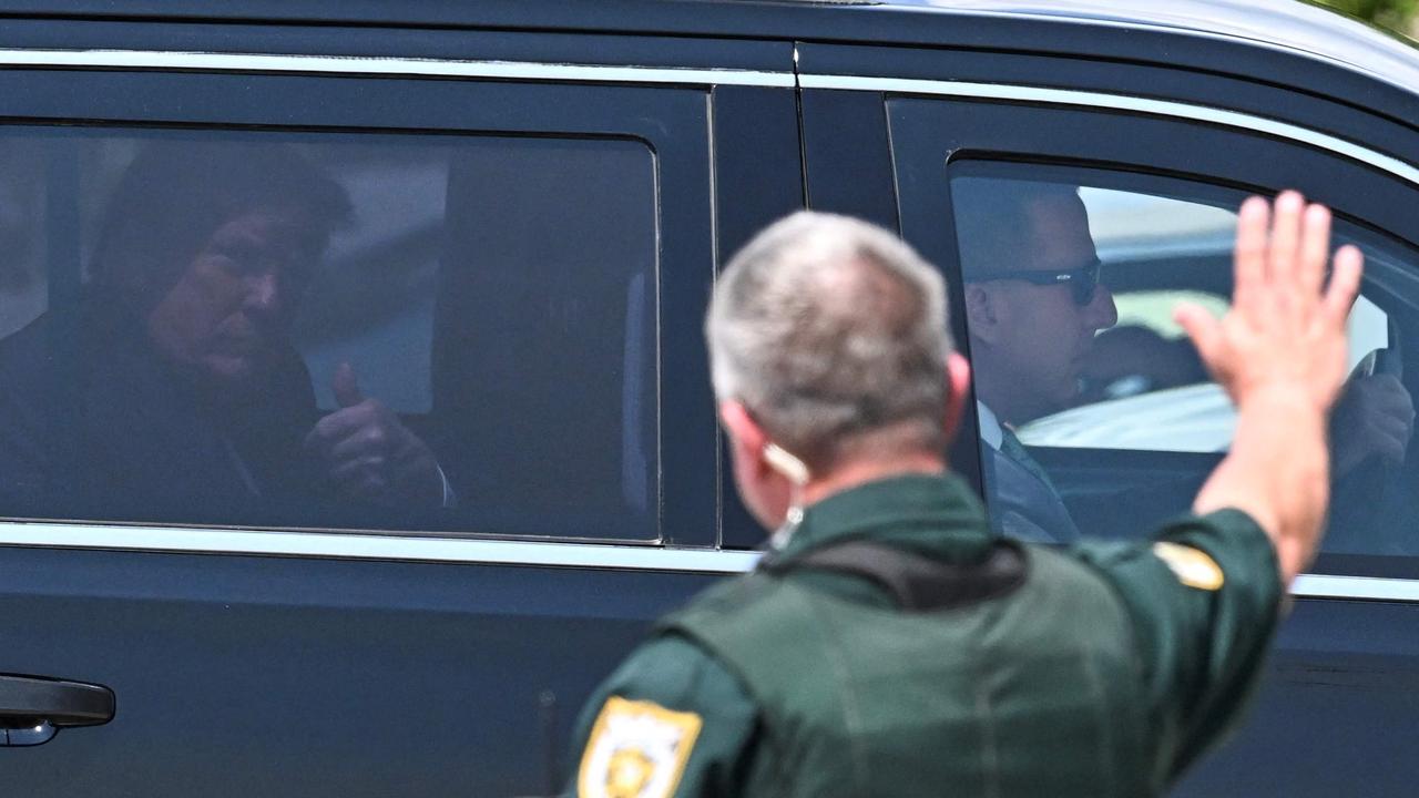 A policeman waves at former US President Donald Trump as he arrives at Palm Beach International Airport in West Palm Beach, Florida. Picture: Chandan Khanna / AFP