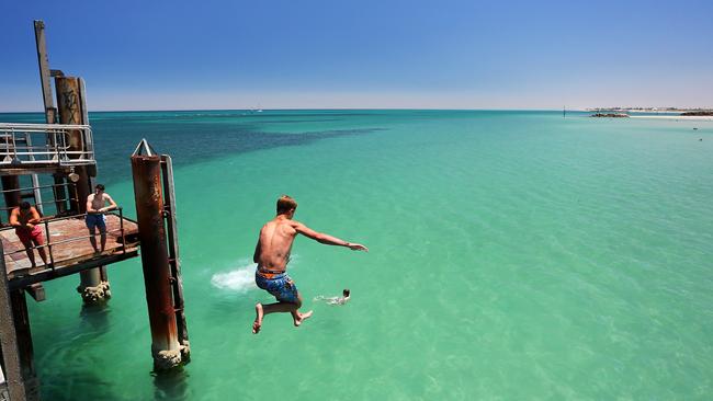 A teenager jumps off Glenelg Beach jetty on January 13, 2014, during a heatwave in Adelaide. On January 16, Adelaide was officially the hottest city on earth. Photo Daniel Kalisz/Getty Images.