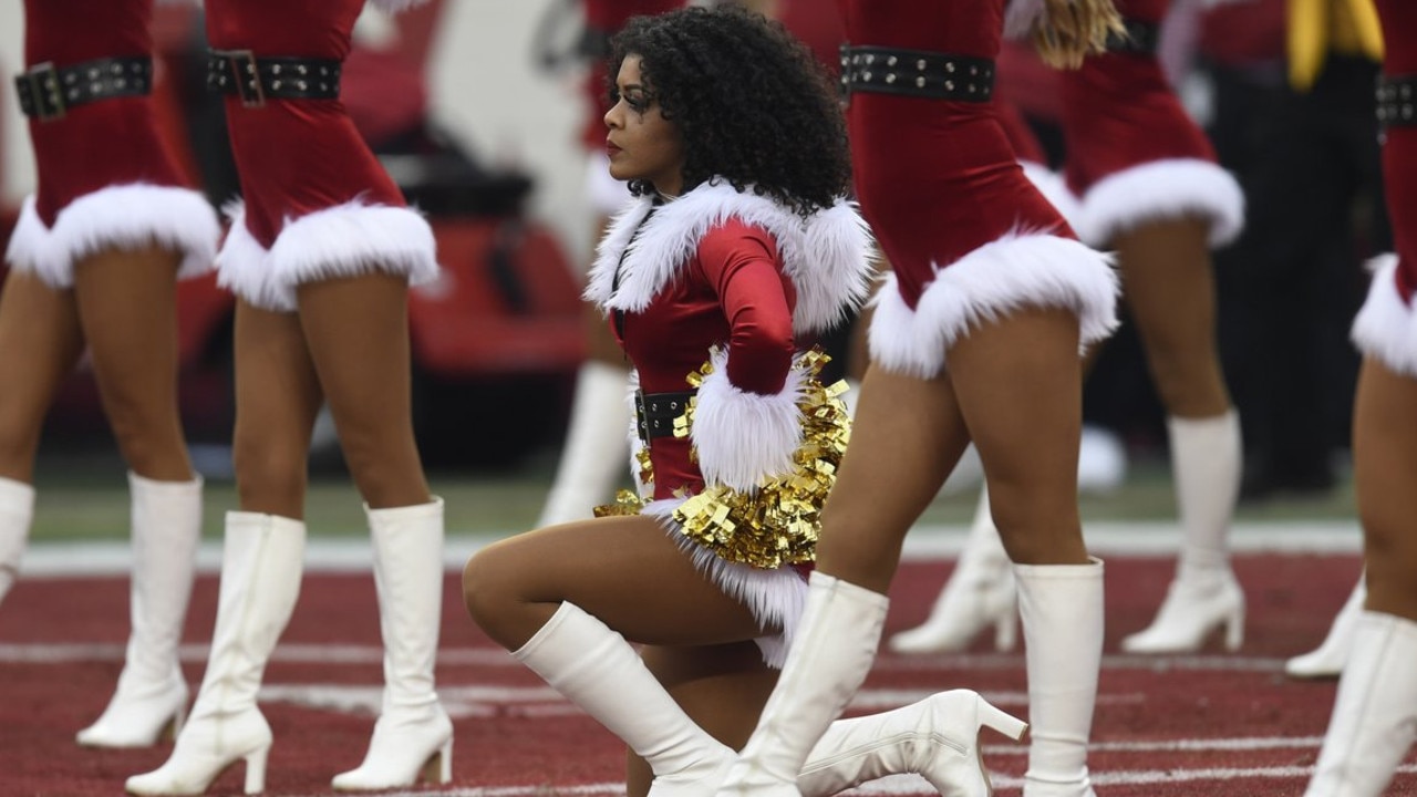 A 49ers cheerleader takes a knee during the national anthem
