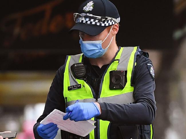 Police issue a fine to a man breaking lockdown laws in Melbourne on August 9, 2020, as the city struggles to cope with a COVID-19 coronavirus outbreak. - Australia's worst-hit Victoria state reported 17 deaths from coronavirus on August 9, making it the country's deadliest day of the pandemic despite a fall in new case numbers. (Photo by William WEST / AFP)