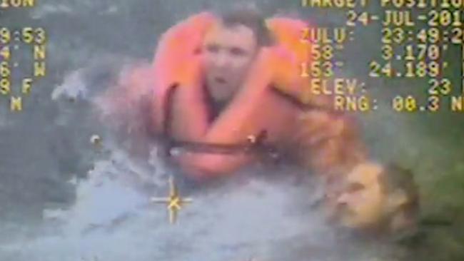 In this still image from video taken on Monday, July 24, 2017, by the Coast Guard, the captain of the fishing vessel Grayling, left, rescues one of his crewmen after the vessel capsized in the Kupreanof Strait near Raspberry Island, Alaska,. The captain jumped into cold, choppy waters to save two of his crew members after their vessel capsized off the Alaska coast. (William Colclough/U.S. Coast Guard via AP)