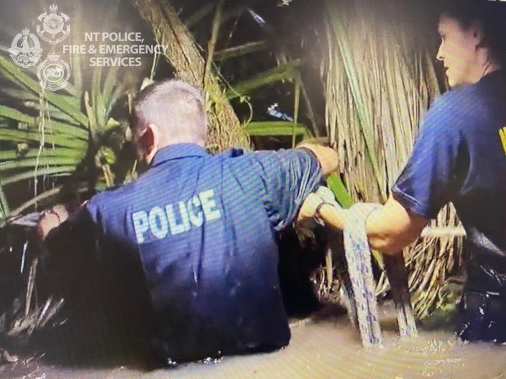 Emergency Services personnel rescue the driver of a car that was swept away in flood water after the driver attempted to cross a submerged rural road in the Virginia area. Picture: NT Police