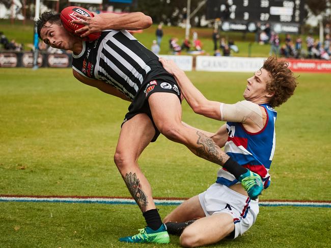 Port's Aidyn Johnson tries to escape from Central's Marcus Barreau at Elizabeth Oval on Saturday. AAP Image/MATT LOXTON