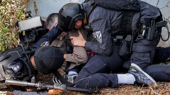 Israeli police and security forces assist a journalist taking cover during an alert for a rocket attack in Israel's southern city of Sderot near the border with Gaza on October 12. Picture: AFP