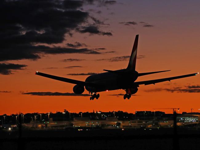 Sydney Airport resembles a ghost town as Sydney enters its 8th week of lockdown due to the Covid 19 pandemic. A Qantas plane lands on the east west runway at sunset. Picture: Toby Zerna