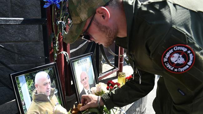 A Wagner member pays tribute to Prigozhin and Dmitry Utkin, a shadowy figure who managed Wagner's operations and allegedly served in Russian military intelligence, at the makeshift memorial in front of the PMC Wagner office in Novosibirsk. Picture: AFP