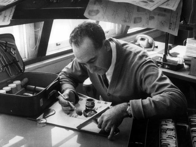 1967: A scientific officer searches for clues on a car's rearvision mirror at a laboratory in Sydney. File picture