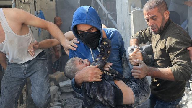 A Palestinian man carries a young victim of the Israeli bombardment in Rafah in the southern Gaza Strip on Tuesday. Picture: AFP