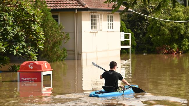 A student paddles around a flooded apartment blocks in St Lucia, after floods and rain swamped Brisbane. Picture: Lyndon Mechielsen