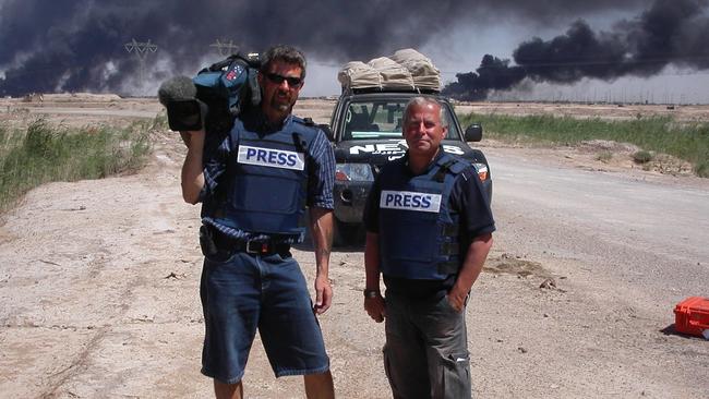 SA television cameraman Rob Brown (l) and Channel 7 journalist Geof Parry wearing press flack jackets reporting on oil fires in Basra City, Iraq, 2003.