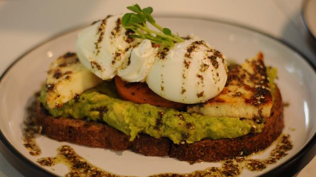 Smashed avo with poached eggs, grilled tomato and haloumi served on rye ($16).