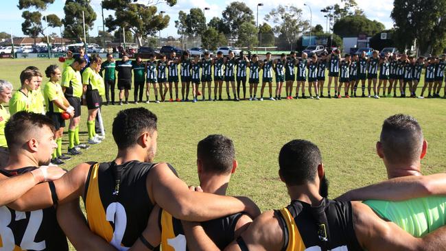 Airport West and Westmeadows players and officials line up before the game in recognition of Anzac Day. Picture: Stuart Milligan