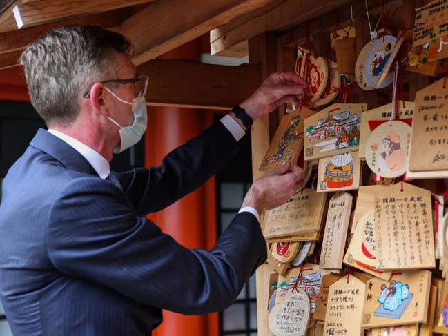 Mr Perrottet hangs an ema board at a shrine. Picture: Toby Zerna/Office of NSW Premier