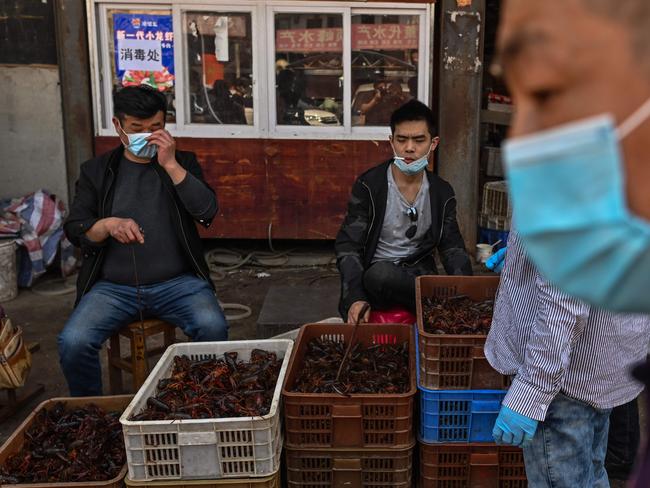 This photo taken on April 15, 2020 shows venders wearing face masks as the offer prawns for sale at the Wuhan Baishazhou Market in Wuhan in China's central Hubei province. - China's "wet" markets have gained a bad international reputation as the coronavirus roiling the world is believed to have been born in stalls selling live game in Wuhan late last year. (Photo by Hector RETAMAL / AFP) / TO GO WITH Health-virus-China,SCENE by Jing Xuan Teng