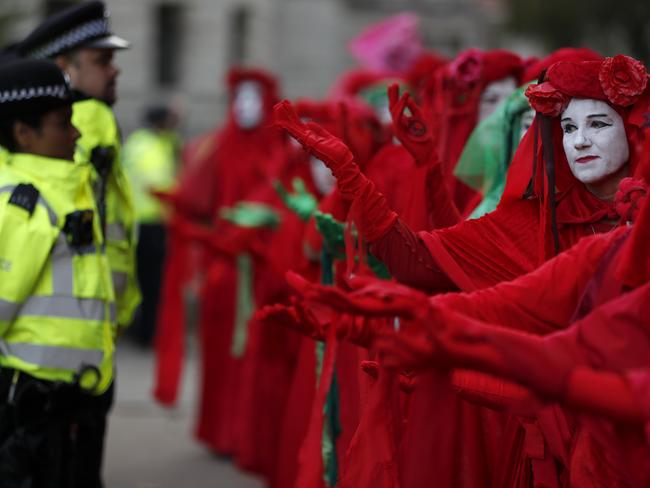 Climate protestors of the group Extinction Rebellion act in front of police officers near Downing Street in London, Wednesday, Oct. 9, 2019. Some hundreds of climate change activists are in central London during a third day of world protests by the Extinction Rebellion movement to demand more urgent actions to counter global warming. (AP Photo/Frank Augstein)