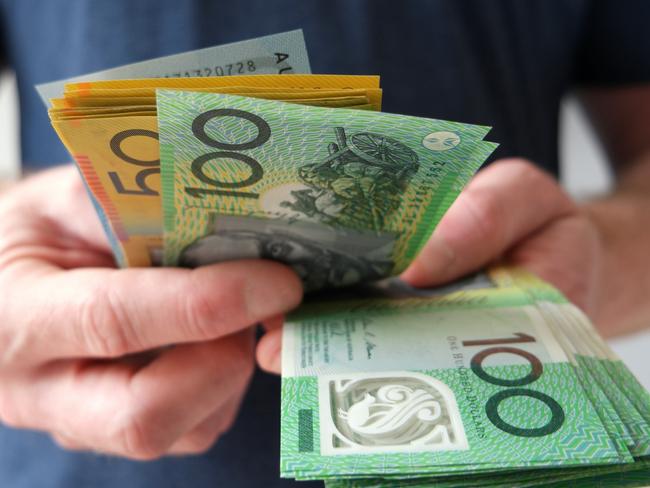 A man counting Australian dollar bills. A picture that describes buying, paying, handing out money, or showing money. Australian cash money generic