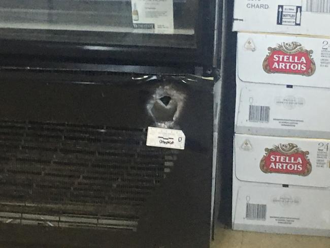 A bullet hole in the bottom right hand corner of a fridge at the liquor store.