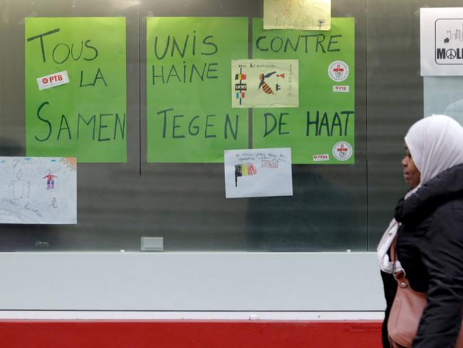 Mixed messages ... A woman walks by a sign which reads 'We are all united against hate' in Molenbeek, Belgium. Source: AP