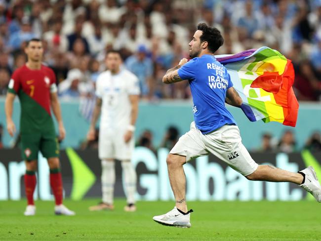 Cristiano Ronaldo of Portugal (left) watches on as a pitch invader wearing a shirt reading "Respect for Iranian woman" and holding a rainbow flag runs across the pitch of the Lusail Stadium. Picture: Francois Nel/Getty Images