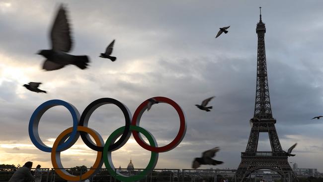 Pigeons fly past the Olympic rings installed on the Esplanade du Trocadero near the Eiffel tower following the Paris' nomination as host for the 2024 Olympics, are pictured on September 14, 2017 in Paris. January 26, 2024 marks the six-month countdown to the opening ceremony kicking off the Paris 2024 Olympic Games which begin on July 26, 2024. (Photo by LUDOVIC MARIN / AFP)