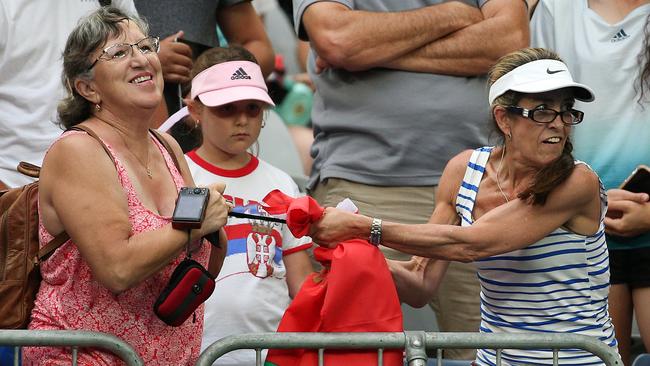 Cathy Willett, right, and another fan fight over a headband worn by Aryna Sabalenka. Picture: AAP