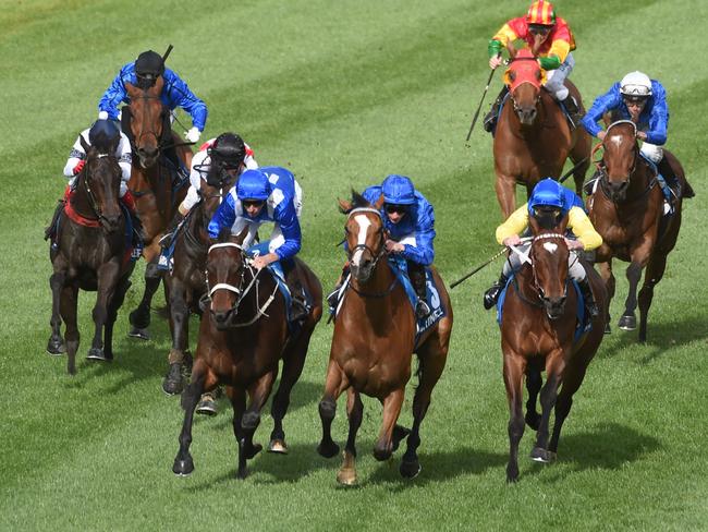 Winx (blue and white silks) is poised to pounce as the riders of Hartnell and Black Heart Bart urge their mounts. Picture: Tony Gough