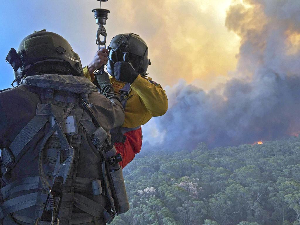 Rural Fire Service employee, Mr Allen Madden prepares to be winched down in the Lithgow area by Petty Officer Aircrewman Jason Wickman from an 808 Squadron MRH90 Taipan Military Support Helicopter over the Grose Valley bushfire in the Blue Mountains National Park. Picture: ADF