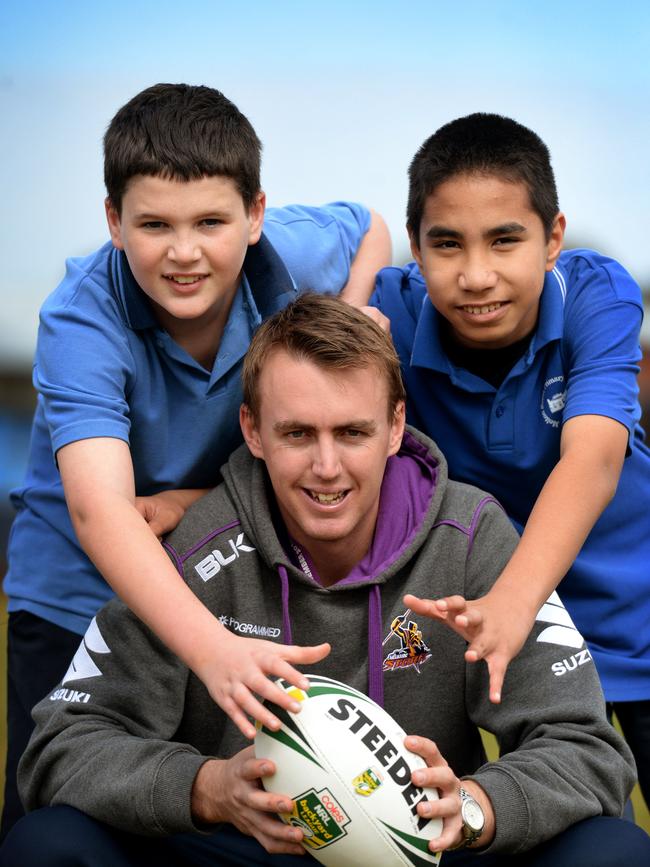 Ryan Walker from Melbourne Storm teaches Melton South Primary School students Rylee and Jonathan how to play rubgy.