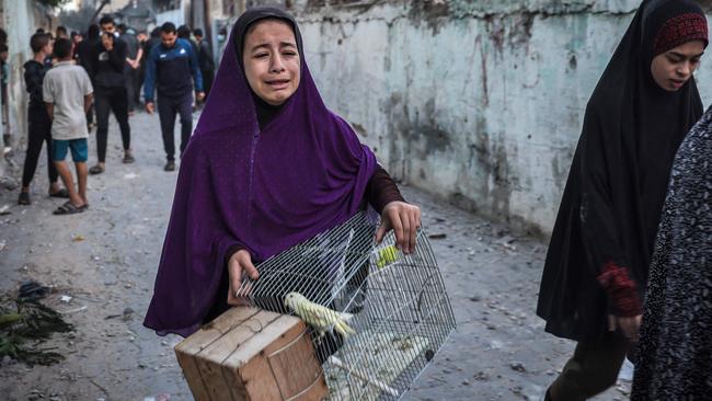 A girl carrying a bird cage flees following an Israeli strike in Gaza, amid the battle between Israel and the Palestinian militant group Hamas. Picture: Mohammed Abed/AFP