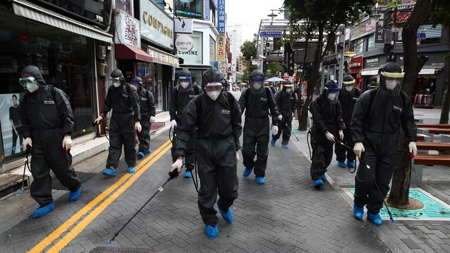 Health officials from Bupyeong district spray anti-septic solution along an alley of markets and shopping district in Incheon, South Korea on Thursday. Picture: Getty Images