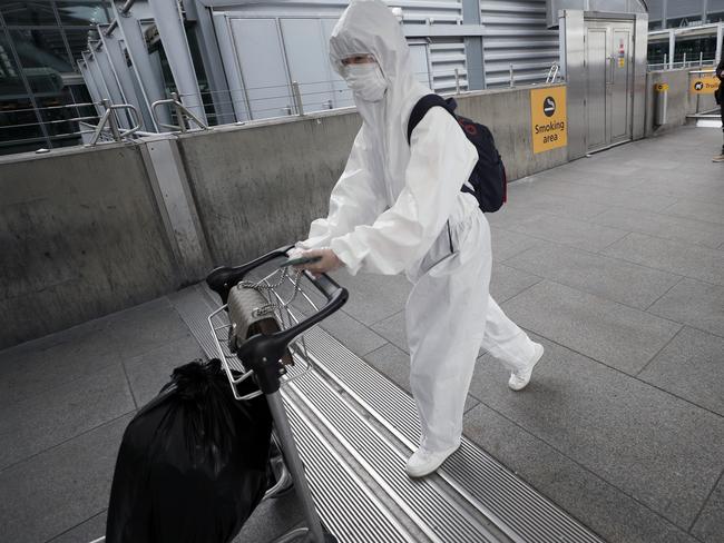 A traveller wearing a protective suit moves her luggage at Heathrow Airport in London. Picture: AP