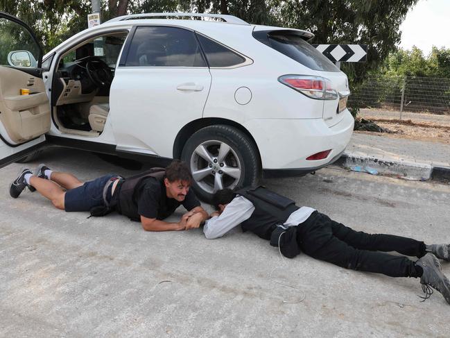 Israeli journalists take cover during a rocket attack from Gaza in the southern Israeli kibbutz of Kfar Aza near the border with the Palestinian territory. Picture: AFP