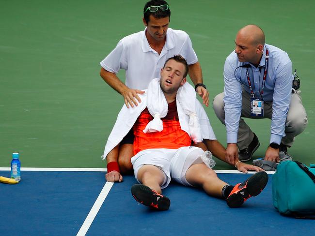 Jack Sock receives assistance from trainer Hugo Gravil for heat exhaustion during the 2015 US Open. The dangers of competing in extreme heat are becoming a subject of increasing concern to sports authorities. Picture: Al Bello/Getty Images