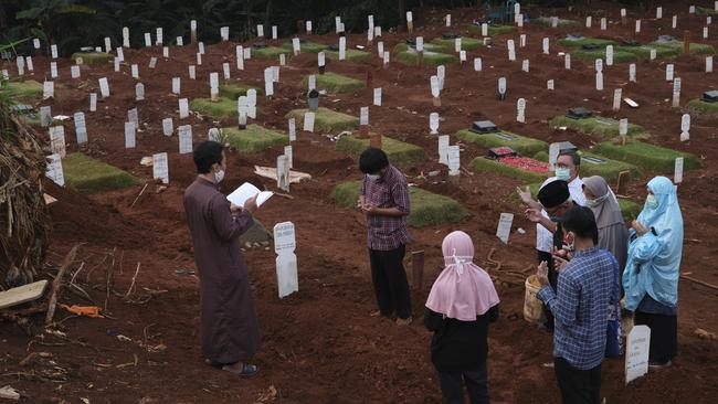 A family prays for a relative at the Muslim section of a COVID-19 gravesite in Jakarta. Picture: Getty Images