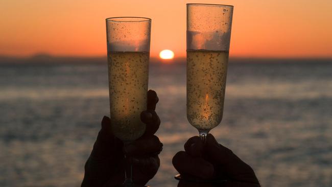 Enjoying a romantic sunset champagne on Havannah Island on the Great Barrier Reef off Townsville. Picture: Paul Dymond / Alamy