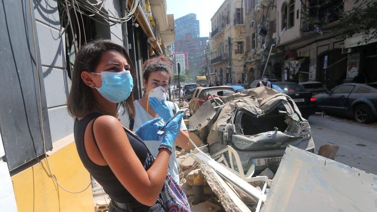 Young women wearing protective masks and gloves against the coronavirus pandemic, stand amid the rubble in Beirut's Gimmayzeh commercial district. Picture: AFP