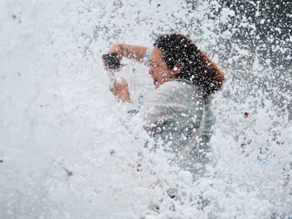 A photographer is battered by a wave in Qingdao City in China's Shandong province. Picture: AFP/Imaginechina