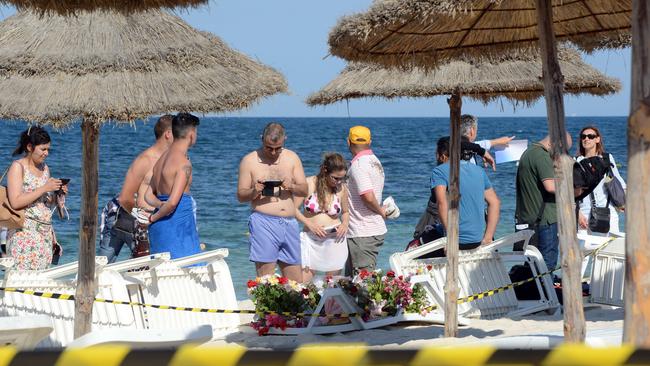 Tourists and journalists take photos of flowers at the site of a shooting attack on the beach in front of the Riu Imperial Marhaba Hotel in Port el Kantaoui.