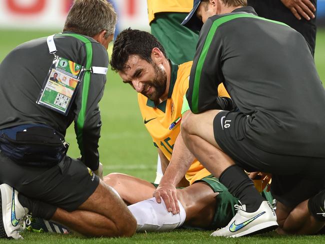 Australia's captain Mile Jedinak (C) receiving treatment to his injured ankle against Kuwait.