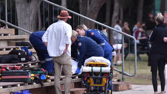 NSW Ambulance paramedics treat a men who suffered a serious head injury after falling from a wheelie bin in the grandstand at Weldon Oval, Curl Curl. Picture: Sebastien Dekker