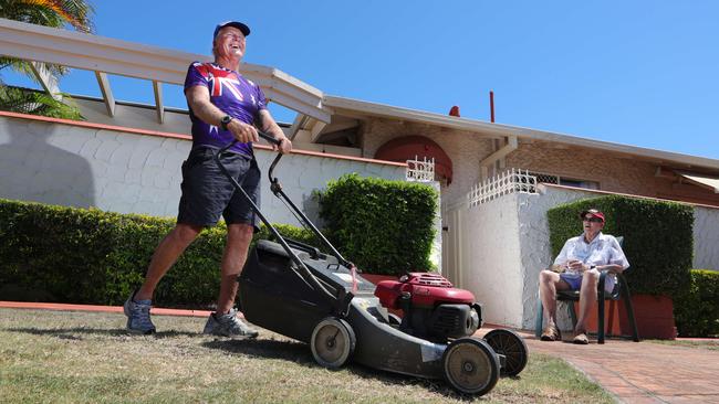 Stroke victim Stephen Wilson 71 of Broadbeach Waters watches on as David Orchard helps out by mowing his lawn. Picture Glenn Hampson