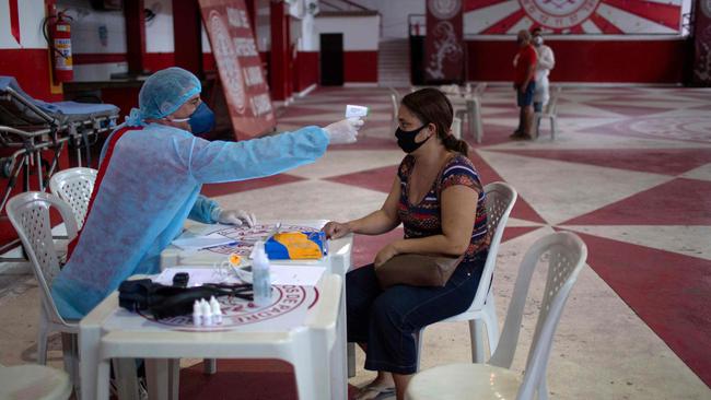 A physician checks the temperature of a woman with coronavirus symptoms at the Unidos de Padre Miguel samba school headquarters in Rio de Janeiro. Picture AFP.