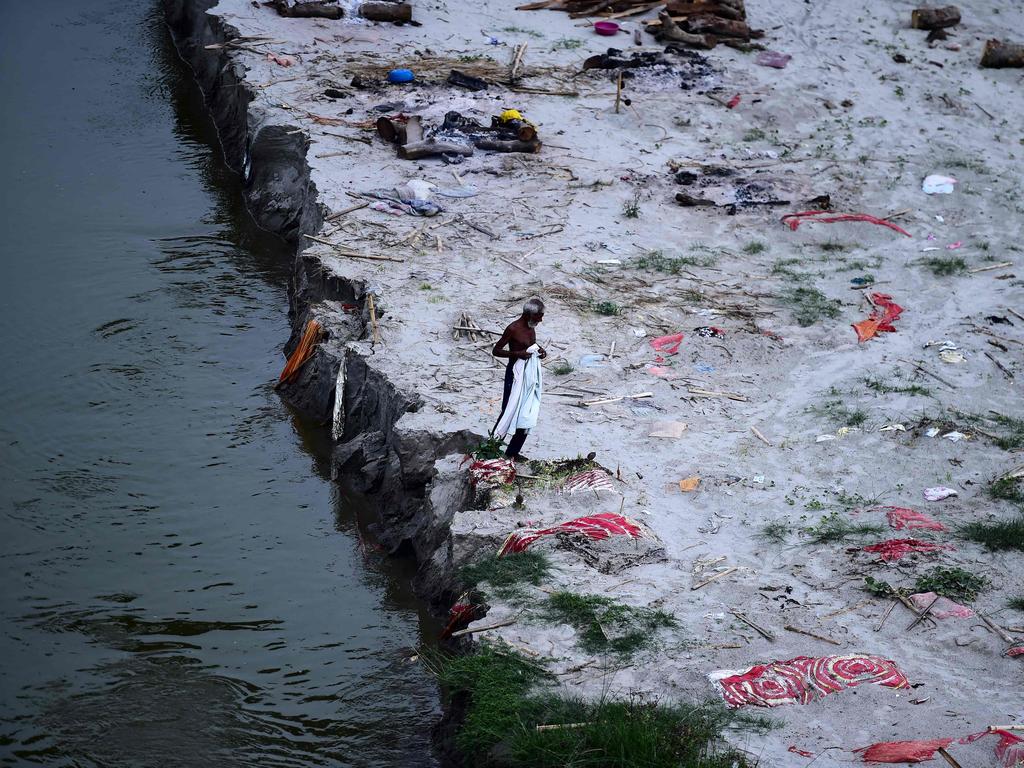 A man walks amid shallow graves in the sand on the banks of Ganges River, at Phafamau ghat in Allahabad, India. Picture: AFP