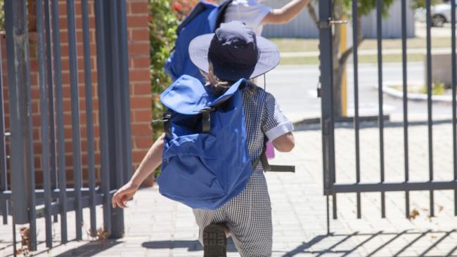 Two school children running out the school gate at the end of the day.