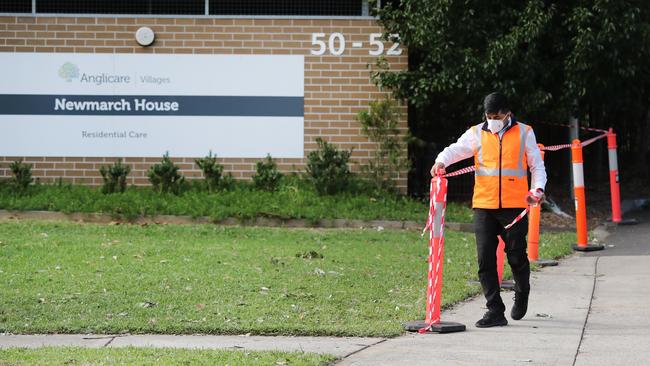 A security guard putting tape up at the entrance of Newmarch House. Picture: Richard Dobson