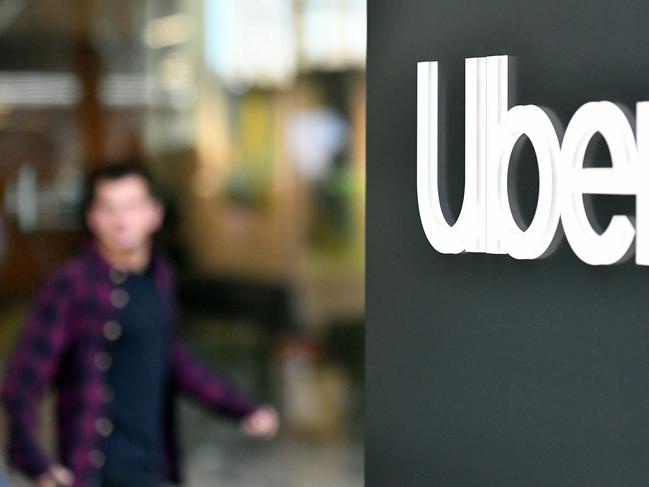 (FILES) In this file photo an Uber logo is seen on a sign outside the company's headquarters location as people protest nearby in San Francisco, California on May 8, 2019. - Uber on May 18, 2020 announced it is cutting a quarter of its global workforce and trimming investment to survive the financial hit to its business from the coronavirus pandemic. The San Francisco-based company is laying off about 3,000 people and stopping some investments unrelated to its core ride-share and delivery businesses, according to chief executive Dara Khosrowshahi. (Photo by Josh Edelson / AFP)