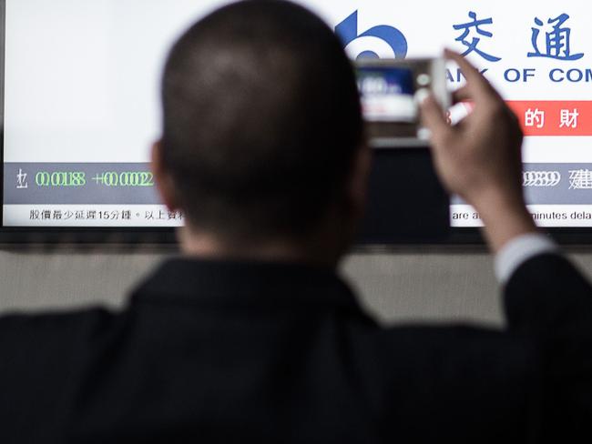 A man takes a picture of an electronic board displaying the benchmark Hang Seng Index in Hong Kong on August 26, 2015. Hong Kong shares ended 1.52 percent lower on August 26, following a late slump in Shanghai as investors shrugged off a Chinese interest rate cut. AFP PHOTO / Philippe Lopez