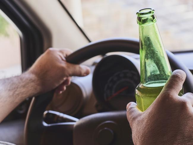 An unrecognizable man drinking beer while driving car. Concepts of driving under the influence, drunk driving or impaired driving. Drink driving generic. Picture: iSTOCK