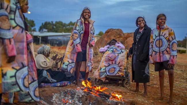 Collaborative spirit: Artist Linda Puna (in wheelchair) of Mimili Maku Arts with family members in the designs for her Unreal Fur collaboration. Picture: Meg Hansen.