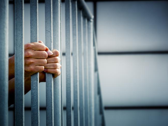 A prisoner behind the jail cell bars .